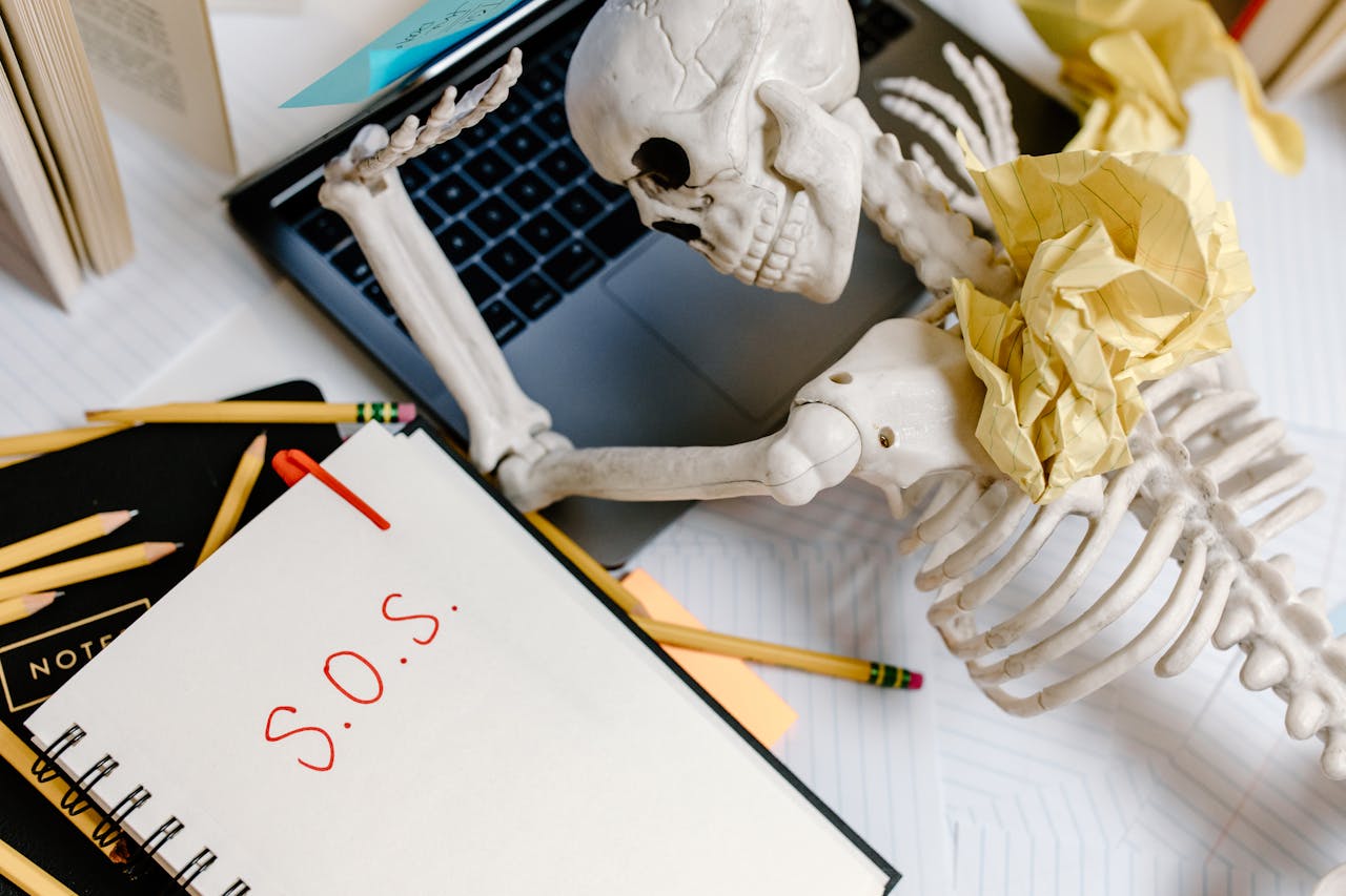 Mastering the First Impression: Your intriguing post title goes here A humorous depiction of office burnout with a skeleton and S.O.S note at a cluttered desk.